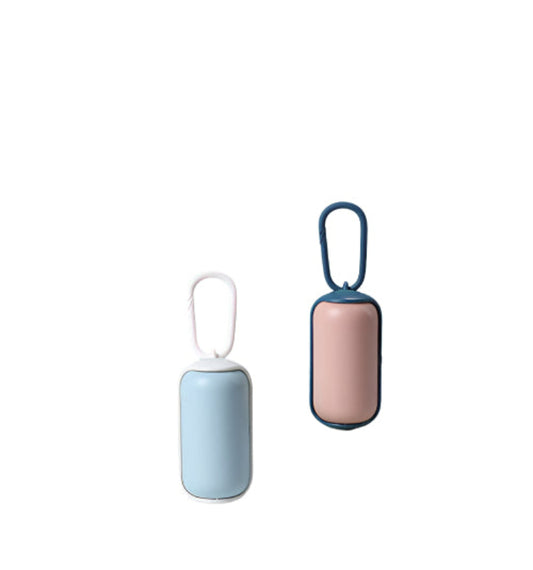 Two small cylindrical devices with handles, one blue and one pink, on a surface with a teal wall in the background.